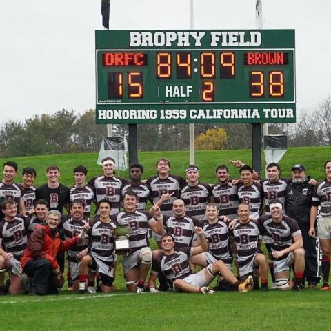 team poses in front of scoreboard after victory