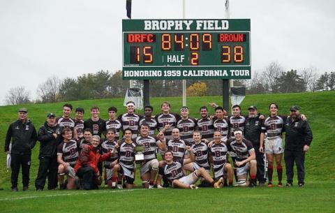 team poses in front of scoreboard after victory