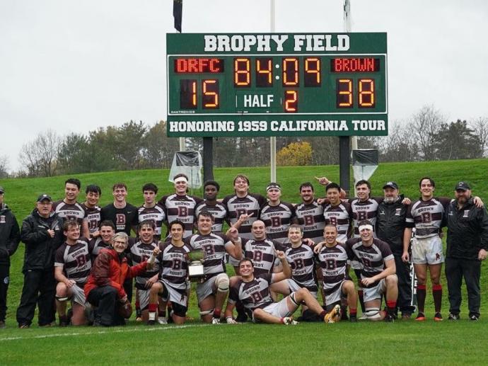 team poses in front of scoreboard after victory